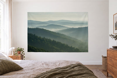 Wandtuch Bewaldete Hügel in Dunstschichten im hellen Schlafzimmer gegenüber dem Bett, rechts eine Holzkommode – Grün