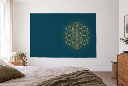 Tapiz flor de la vida en dorado y azul en el dormitorio claro frente a la cama, cómoda de madera a la derecha – dorado y azul
