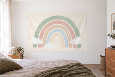 Tapiz arcoíris boho con nubes en el dormitorio claro frente a la cama, cómoda de madera a la derecha – salvia y rosa