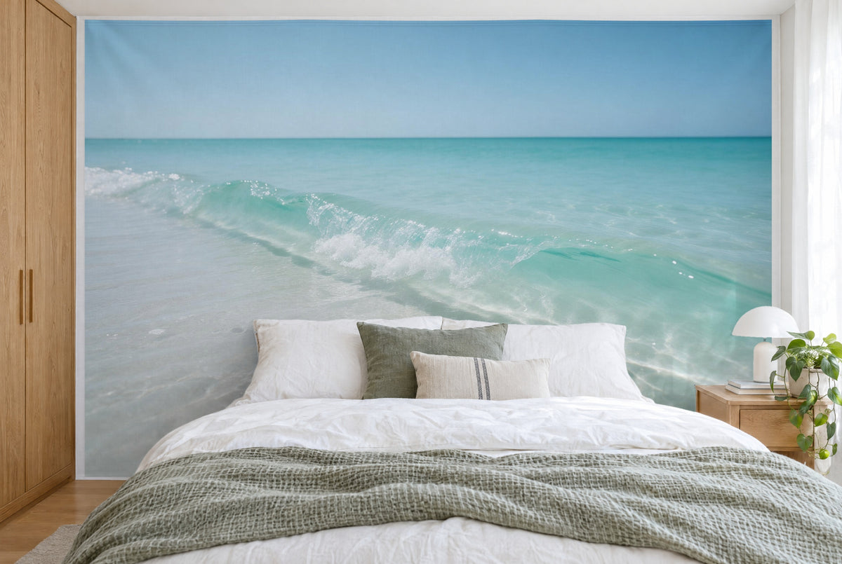 Bedruckter Stoff im XXL-Format: flache Welle rollt über hellen Sand, wandfüllend hinter dem Bett