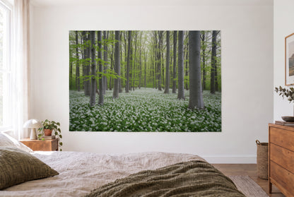 Wandtuch Buchenwald mit Bärlauchblüten im hellen Schlafzimmer gegenüber dem Bett, rechts eine Holzkommode – Grün und Weiss