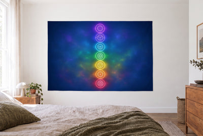 Tenture colonne de chakras arc-en-ciel dans une chambre claire face au lit, une commode en bois à droite – bleu nuit