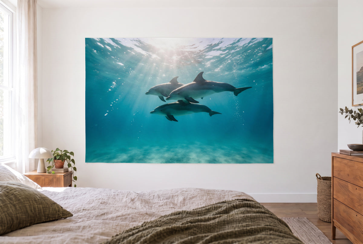 Wandtuch Delfine im Sonnenlicht im hellen Schlafzimmer gegenüber dem Bett, rechts eine Holzkommode – Türkis und Blau