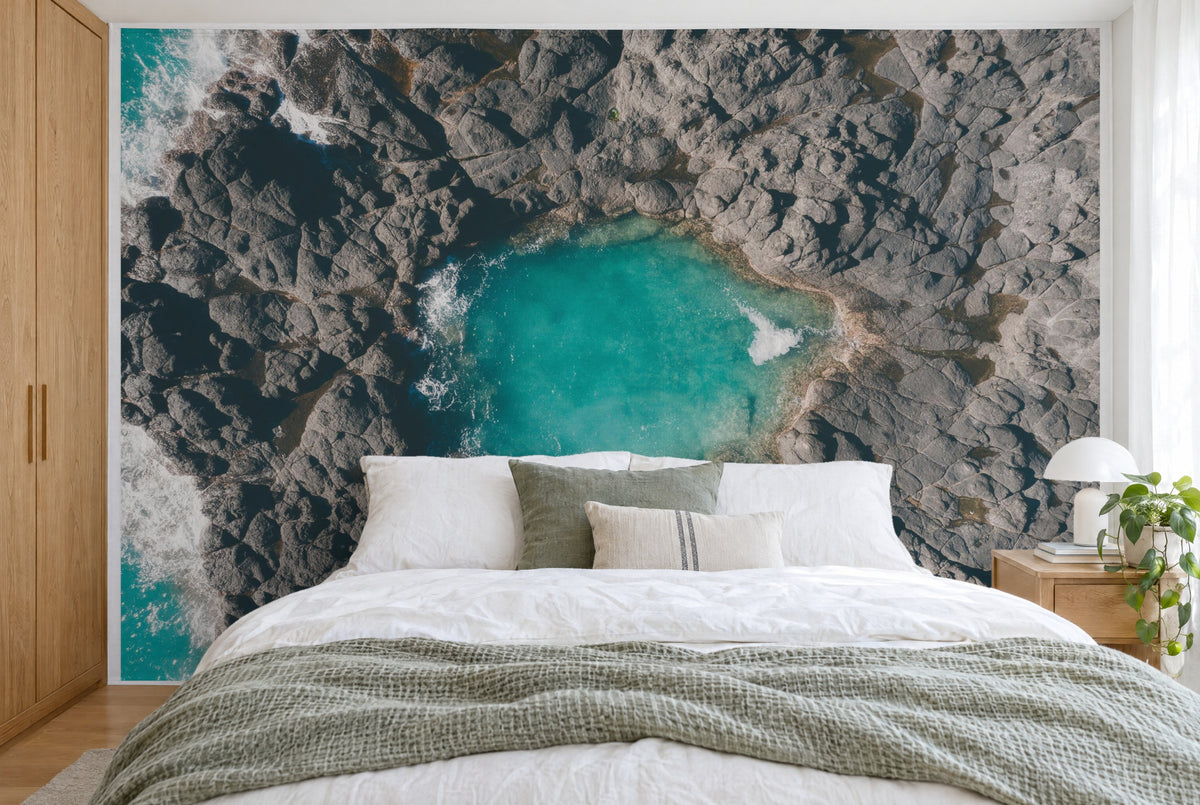 XXL printed fabric: turquoise rock pool in the centre, sea with surf at left, filling the wall behind the bed