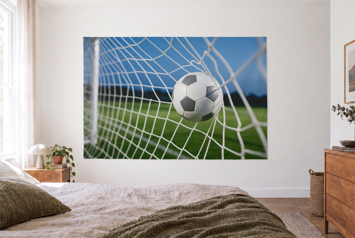 Wandtuch Fussball im Tornetz im hellen Schlafzimmer gegenüber dem Bett, rechts eine Holzkommode – Grün, Weiss und Blau
