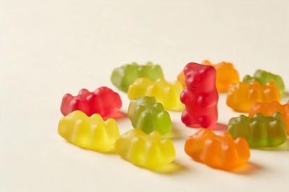 Bunte Gummibärchen auf Creme, rechts ein stehendes rotes Bärchen, als Wandtuch, auf Stoff gedruckt – Rot, Gelb und Grün