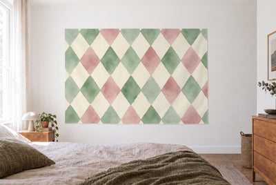 Tenture losanges arlequin sauge et vieux rose dans une chambre claire face au lit, commode en bois à droite