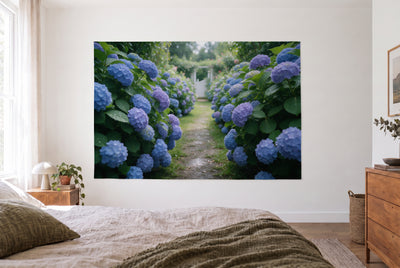 Wandtuch Hortensiengarten im Sommer im hellen Schlafzimmer gegenüber dem Bett, rechts eine Holzkommode – Blau und Violett