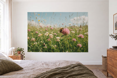Wandtuch Hummel an der Kleeblüte im hellen Schlafzimmer gegenüber dem Bett, rechts eine Holzkommode – Rosa, Grün und Gelb