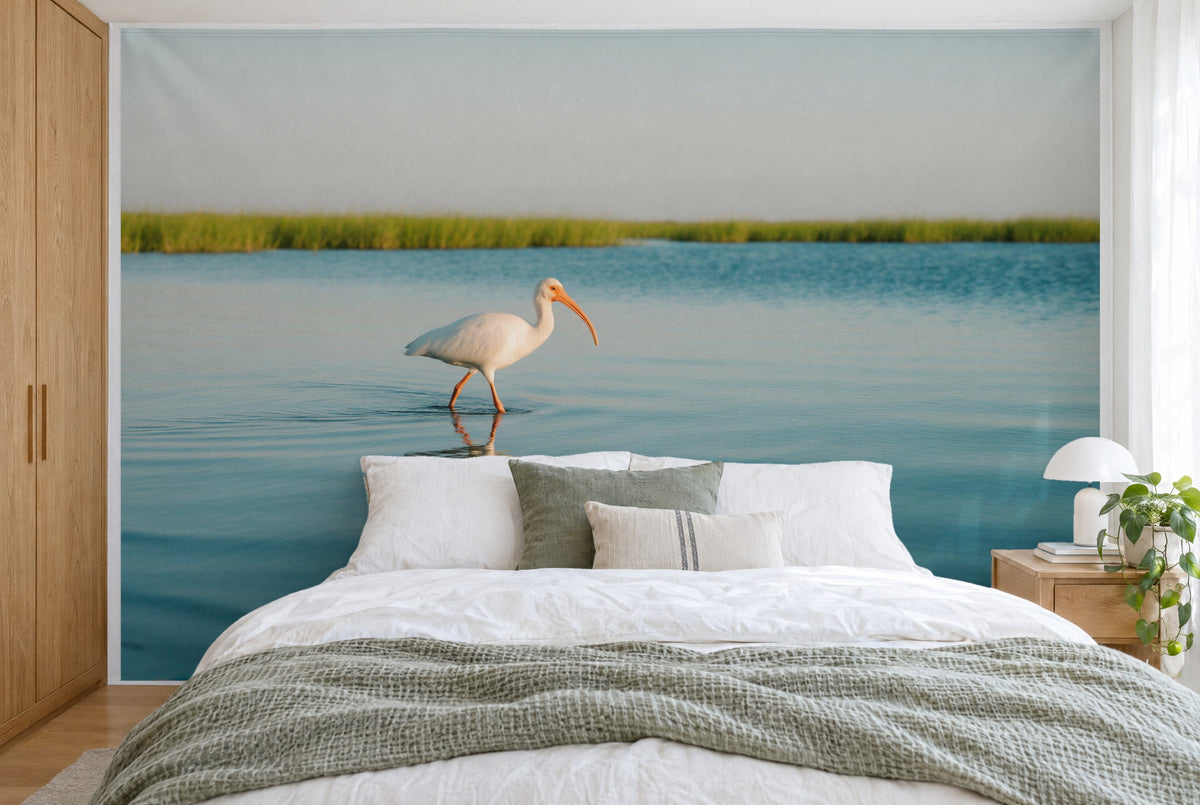 Bedruckter Stoff im XXL-Format: weisser Ibis links der Mitte im Lagunenwasser vor grünem Schilf, wandfüllend hinter dem Bett
