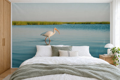 Bedruckter Stoff im XXL-Format: weisser Ibis links der Mitte im Lagunenwasser vor grünem Schilf, wandfüllend hinter dem Bett