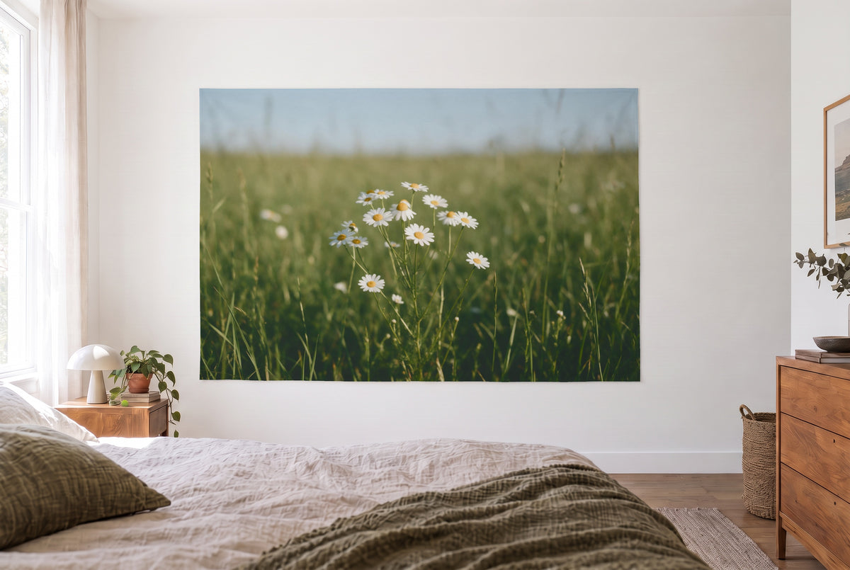 Wandtuch Kamillenblüten auf der Wiese im hellen Schlafzimmer gegenüber dem Bett, rechts eine Holzkommode – Weiss und Grün