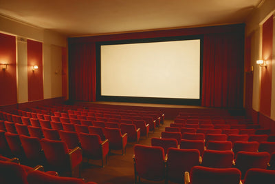 Empty cinema with red velvet seats before a bright screen and curtains, tapestry printed on fabric – red and gold