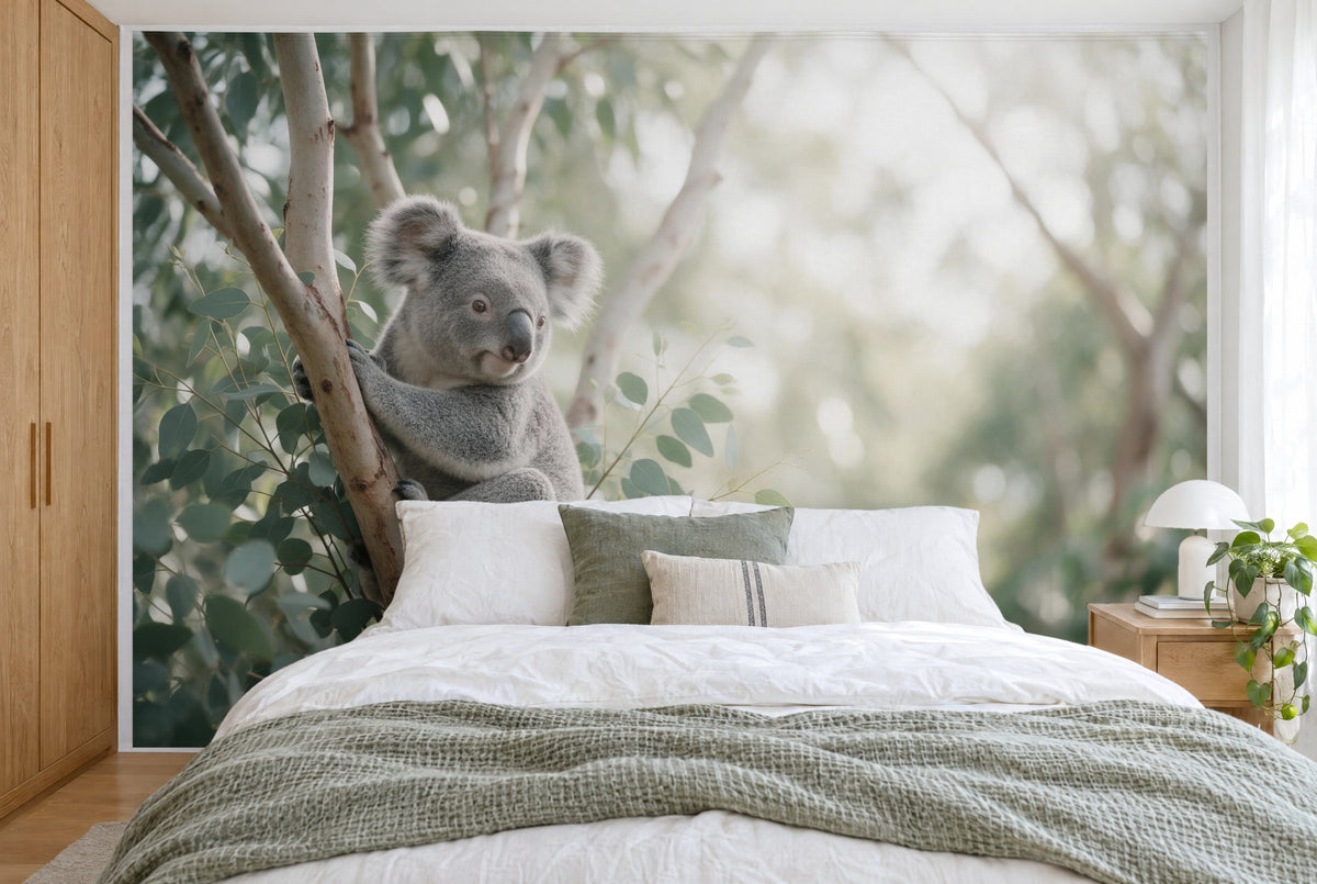Bedruckter Stoff im XXL-Format: Koala links am hellen Eukalyptusast, grüner Wald unscharf rechts, wandfüllend hinter dem Bett