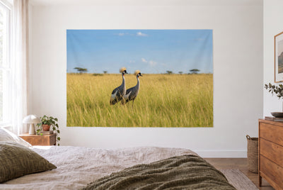 Tenture grues couronnées dans une chambre claire face au lit, commode en bois à droite – or, vert et bleu