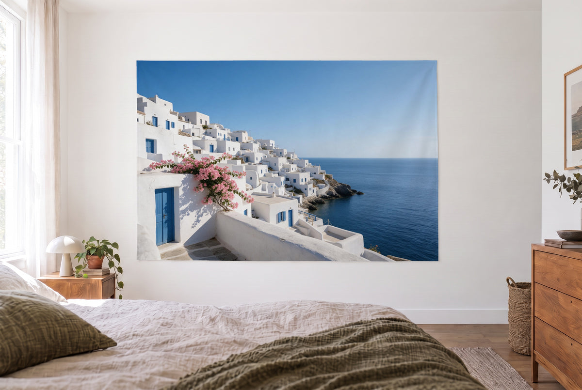 Tenture village côtier en Grèce dans une chambre claire face au lit, commode en bois à droite – blanc et bleu