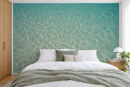 Bedruckter Stoff im XXL-Format: helles Lichtnetz links auf klarem Wasser, rechts ruhiger Sand, wandfüllend hinter dem Bett