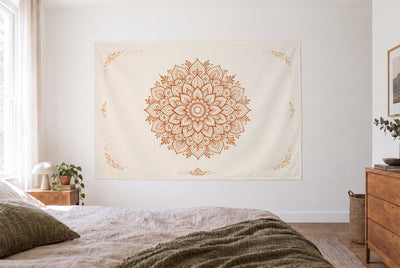 Tenture mandala motif henné marron dans une chambre claire face au lit, une commode en bois à droite – beige