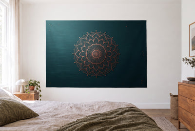 Tenture mandala pétrole et cuivre dans une chambre claire face au lit, une commode en bois à droite – reflets cuivrés