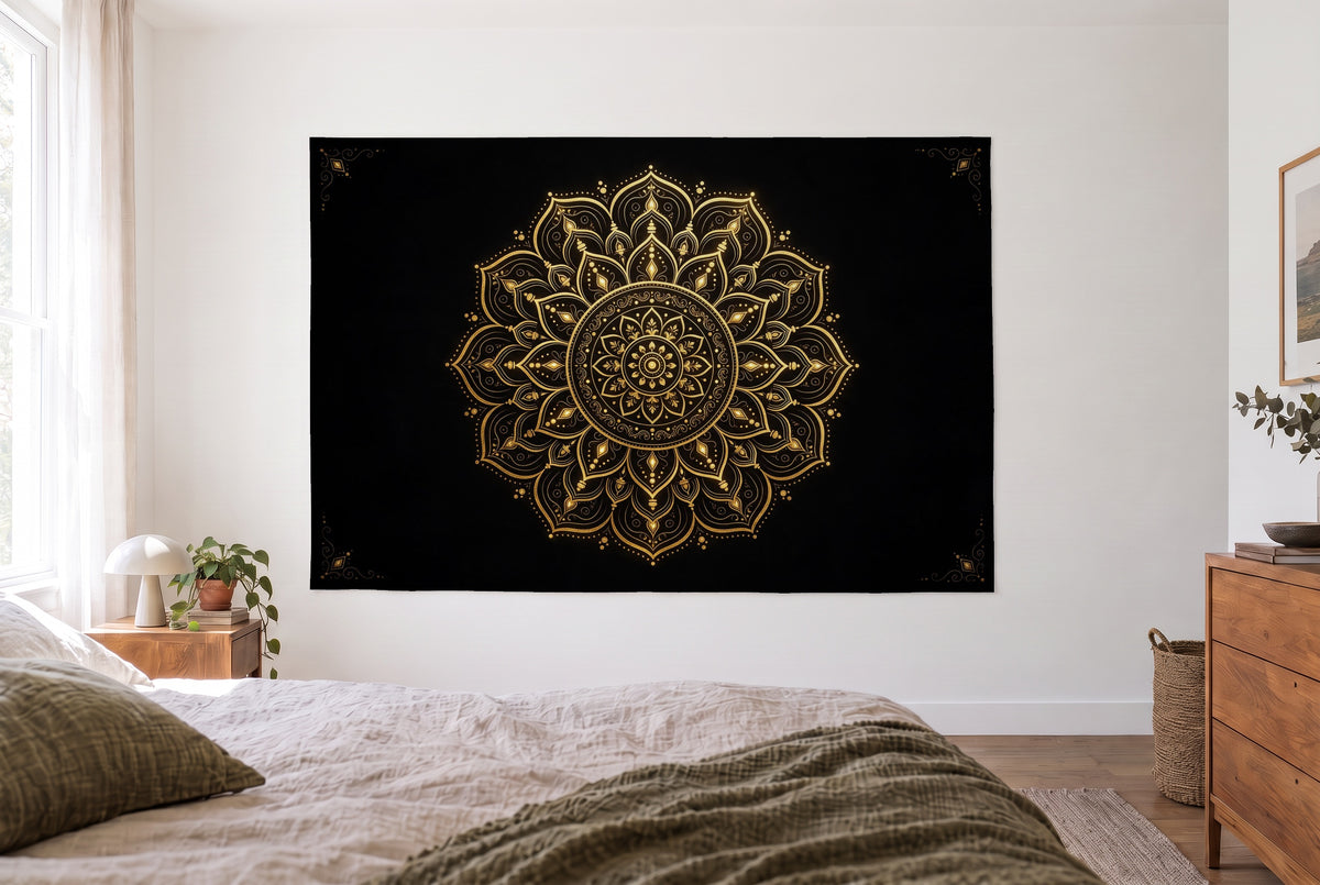 Tenture mandala noir et or dans une chambre claire face au lit, une commode en bois à droite – noir et or