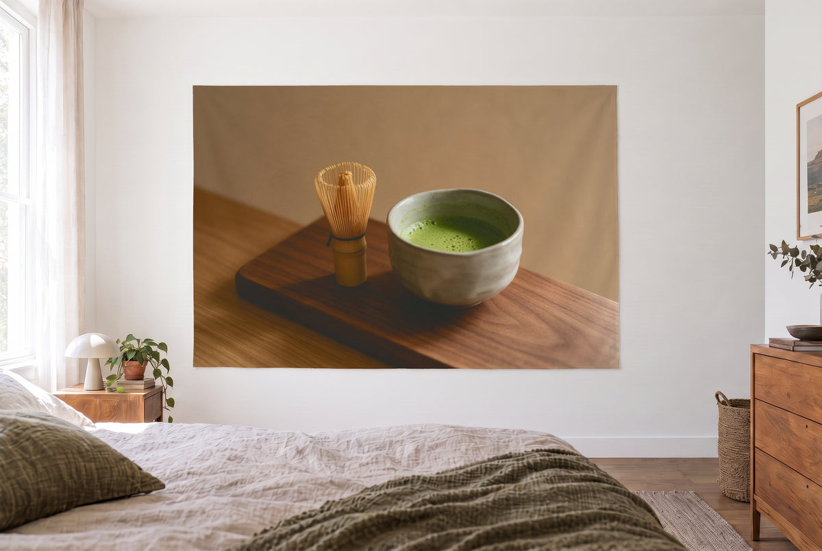 Wandtuch Matcha-Teeschale auf Holz im hellen Schlafzimmer gegenüber dem Bett, rechts eine Holzkommode – Grün und Braun