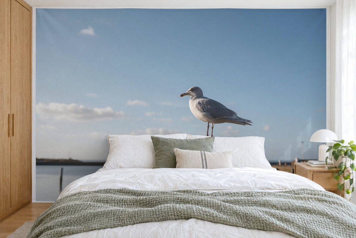 Bedruckter Stoff im XXL-Format: silbergraue Möwe rechts auf dem Hafenpfahl vor Himmelblau, wandfüllend hinter dem Bett