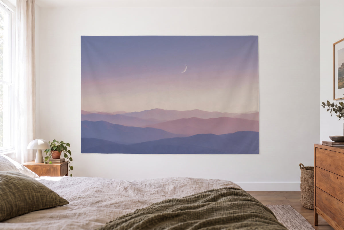 Pastel Mountains under the Moon tapestry in a bright bedroom opposite the bed, wooden dresser on the right – blue and pink