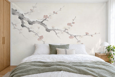 XXL printed fabric: gnarled plum branch with white and pink blossoms at upper left, filling the wall behind the bed
