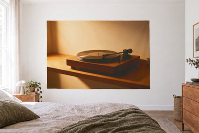 Wandtuch Plattenspieler mit Schallplatte im hellen Schlafzimmer gegenüber dem Bett, rechts eine Holzkommode – Braun und Gold