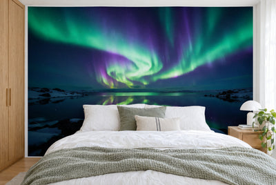 Tela impresa XXL: auroras boreales verdes y violetas en el centro sobre el lago polar en calma, cubre la pared tras la cama