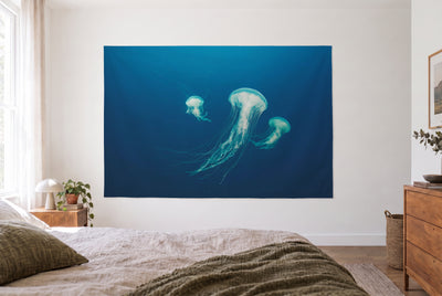 Wandtuch Quallen im tiefen Blau im hellen Schlafzimmer gegenüber dem Bett, rechts eine Holzkommode – Blau und Türkis