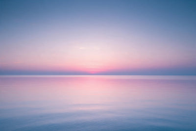 Cielo rosa sobre un mar liso como un espejo con una línea de horizonte nítida, tapiz impreso en tela – rosa y azul