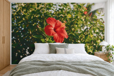Tela impresa XXL: flor de hibisco roja con capullos a la izquierda ante verdor tropical, pared entera tras la cama