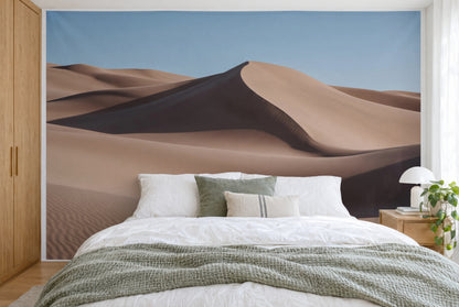 Bedruckter Stoff im XXL-Format: geschwungene Sanddünen unter blauem Himmel, wandfüllend hinter dem Bett