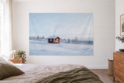 Sauna cabin in the snow tapestry in the bright bedroom opposite the bed, wooden dresser on the right – white, red and blue
