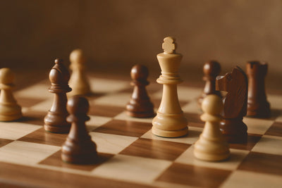 Schachfiguren aus hellem und dunklem Holz in der Partie, König im Fokus, als Wandtuch, auf Stoff gedruckt – Braun und Beige