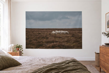 Sheep on the heath tapestry in a bright bedroom opposite the bed, wooden dresser on the right – brown and grey