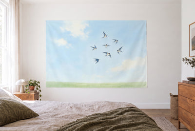 Tenture murale Hirondelles en vol dans la chambre claire face au lit, commode en bois à droite – bleu et vert