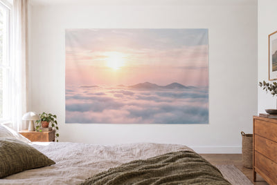 Rising sun over the sea of clouds tapestry in a bright bedroom opposite the bed, wooden dresser on the right – pink