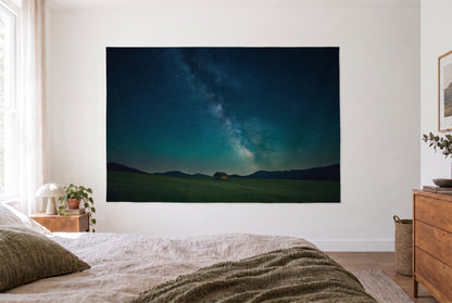 Starry sky alpine hut tapestry in a bright bedroom opposite the bed, wooden dresser at right – blue and green
