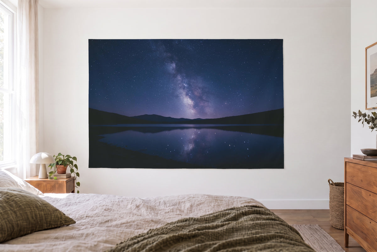 Wandtuch Sternenhimmel über Bergsee im hellen Schlafzimmer gegenüber dem Bett, rechts eine Holzkommode – Blau und Violett