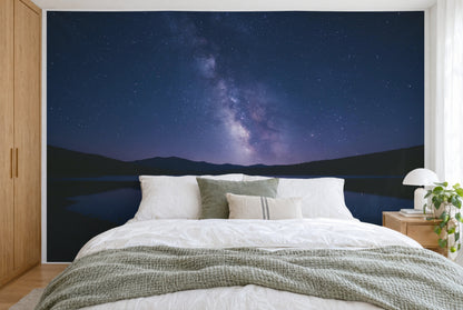 Bedruckter Stoff im XXL-Format: Milchstrasse über dunkler Bergsilhouette, wandfüllend hinter dem Bett