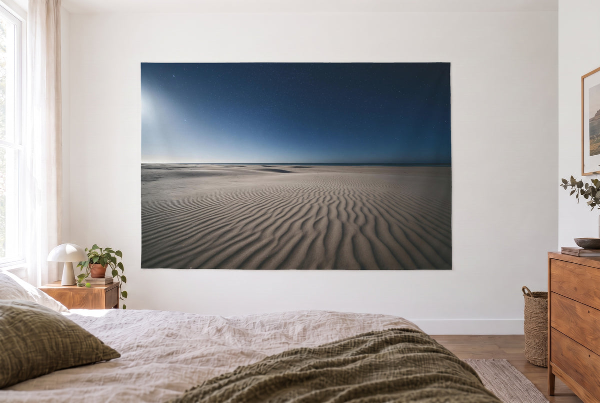 Wandtuch Sternenhimmel über Dünenstrand im hellen Schlafzimmer gegenüber dem Bett, rechts eine Holzkommode – Blau und Beige