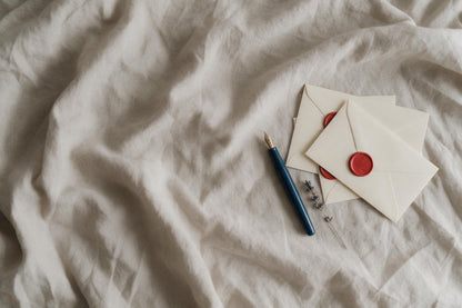 Nature morte : stylo plume, trois lettres au cachet rouge à droite sur lin, tenture murale imprimée sur tissu – rouge et bleu