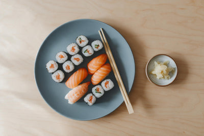Bunte Sushi-Stücke mit Lachs-Nigiri und Maki auf grauer Platte, als Wandtuch, auf Stoff gedruckt – Rosa und Braun