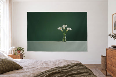 Tenture arums blancs sur fond sombre dans une chambre claire face au lit, commode en bois à droite – vert