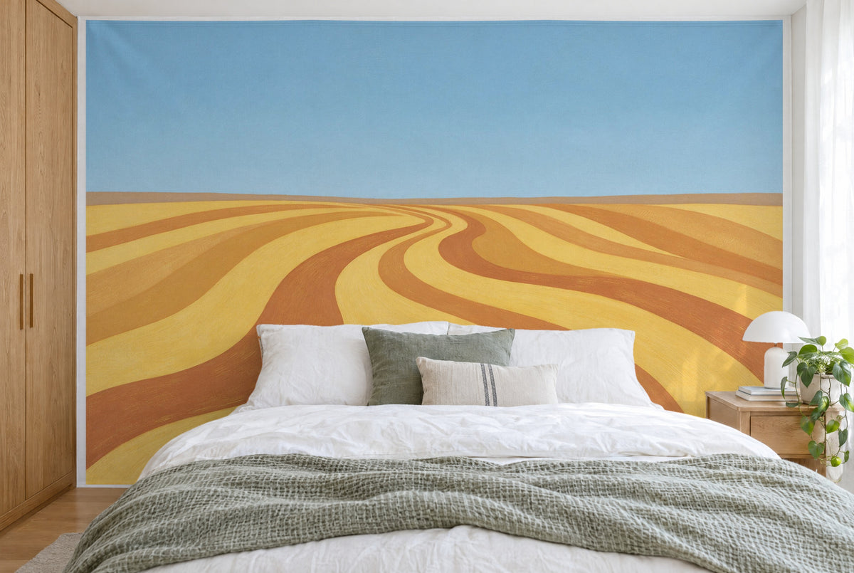 Bedruckter Stoff im XXL-Format: geschwungene Gold-Feldbänder unter blauem Himmel, wandfüllend hinter dem Bett
