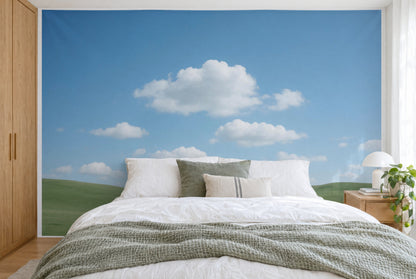 Bedruckter Stoff im XXL-Format: weisse Quellwolken über sanften grünen Hügeln, wandfüllend hinter dem Bett