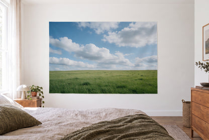 Tenture murale ciel nuageux sur prairie d'été dans la chambre claire face au lit, commode en bois à droite – bleu vert