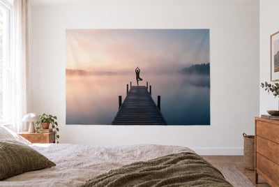 Yoga silhouette by the lake tapestry in a bright bedroom opposite the bed, wooden dresser on the right – peach and misty blue